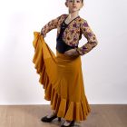 Torera infantil flamenca Feria de Paralola. La modelo luce la torera Feria en color albero combinada con una falda Trini también en color albero, todo de Paralola tu vestuario flamenco.